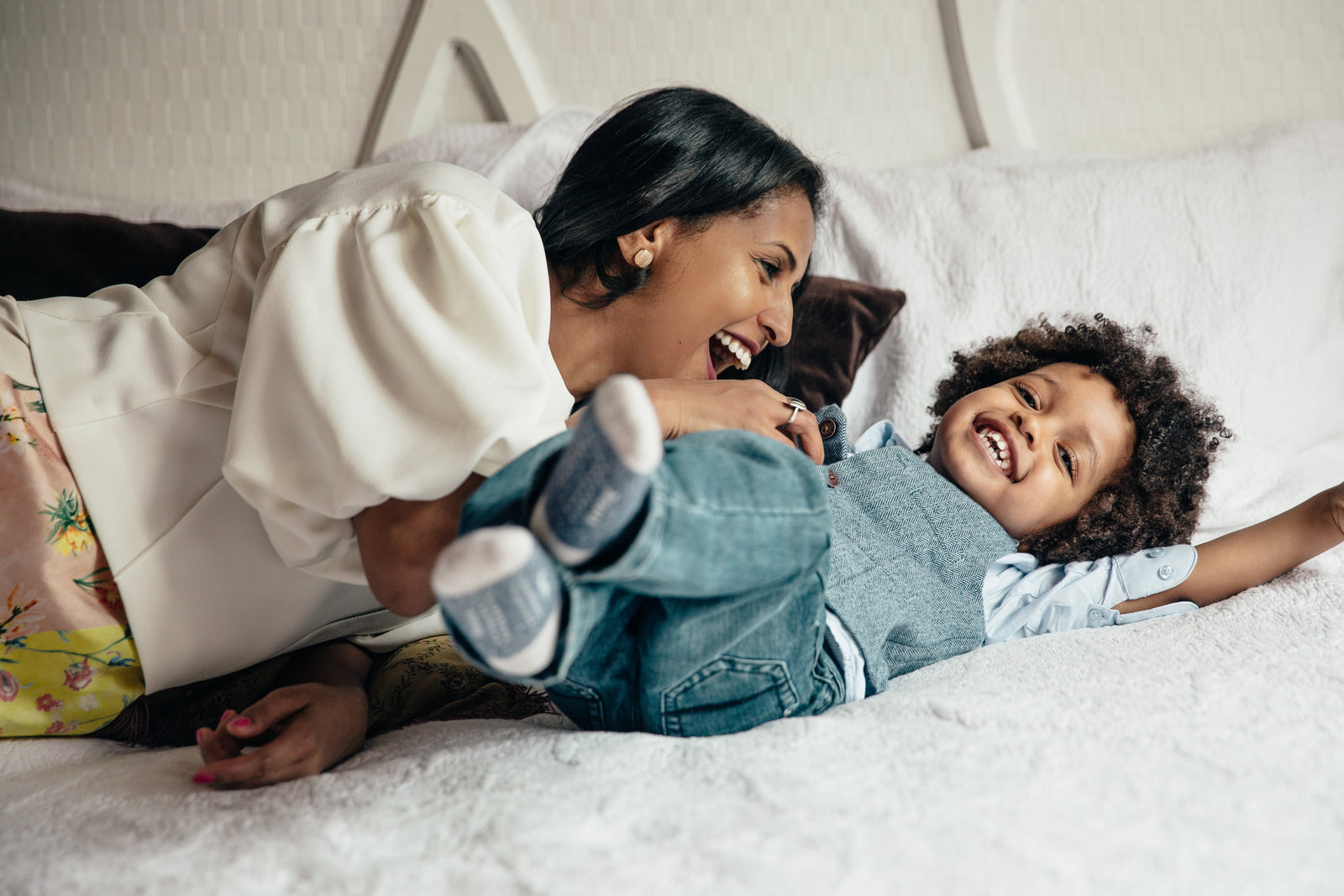 Mother and child playing on bed. Mother tickling son's middle.