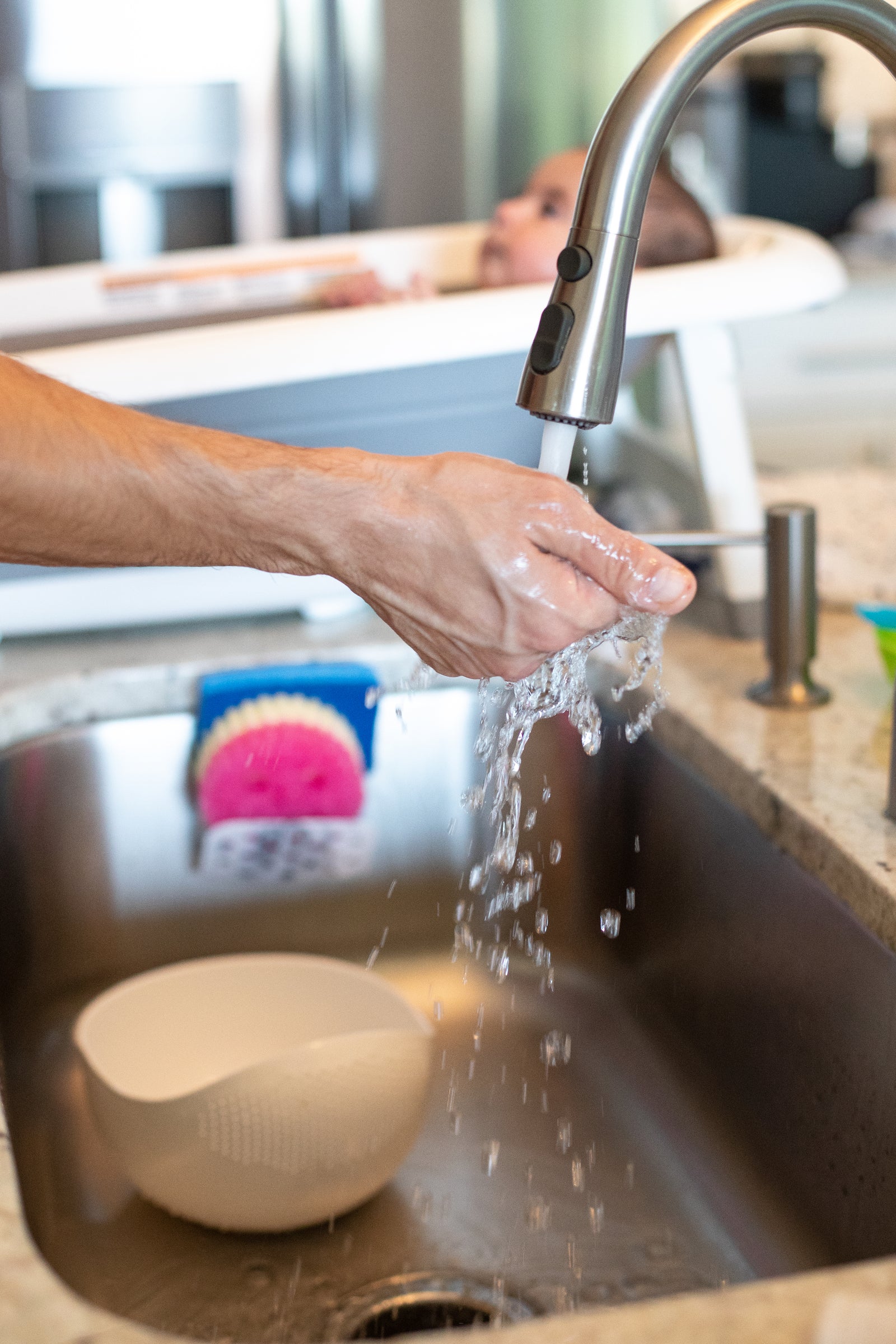 Person holding hand under running water in the kitchen.