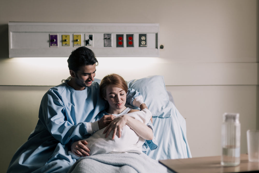 Father and mother in a hospital bed admiring their newborn.